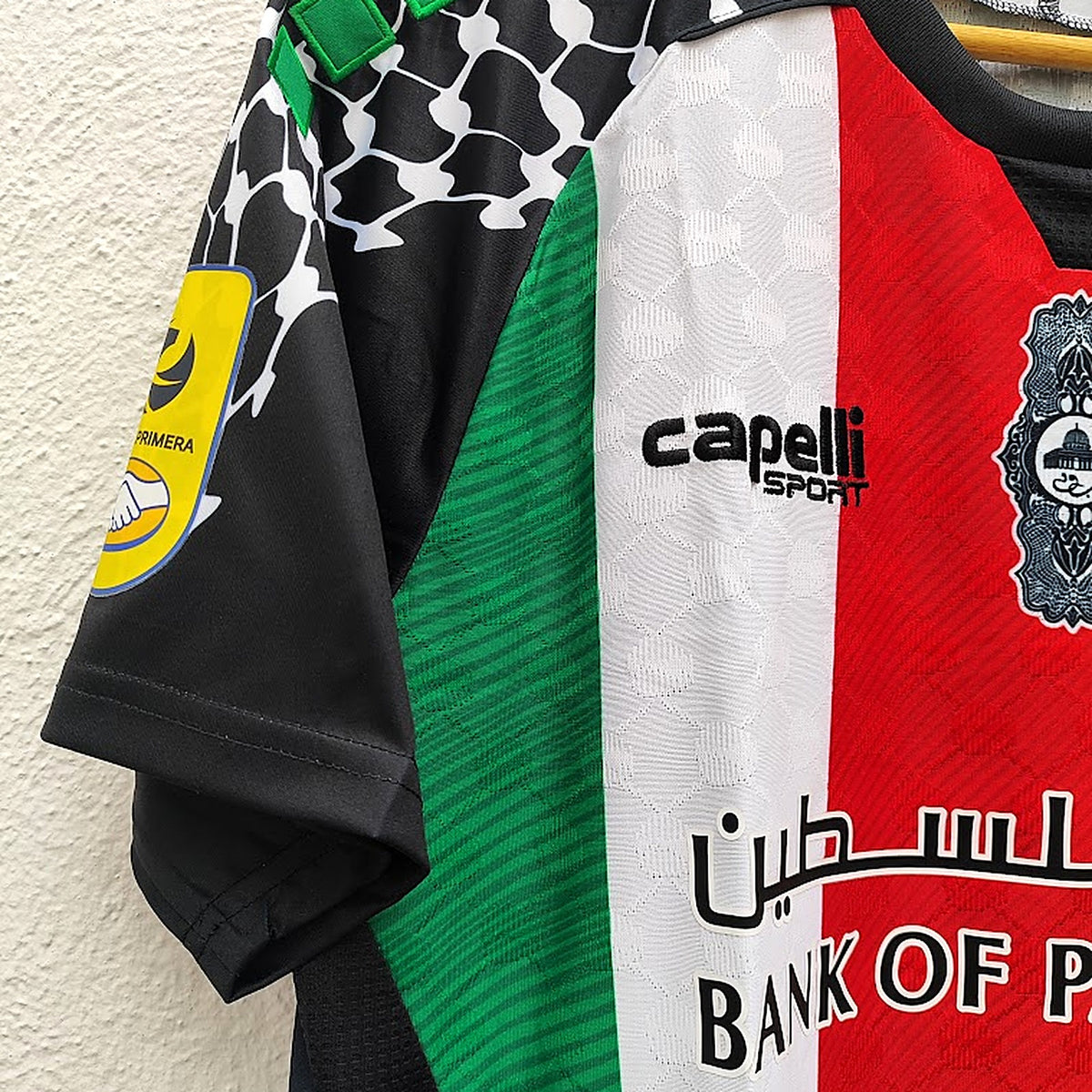 Detalhe do ombro com padrão kufiya e quadrados verdes – Palestino Home 2026